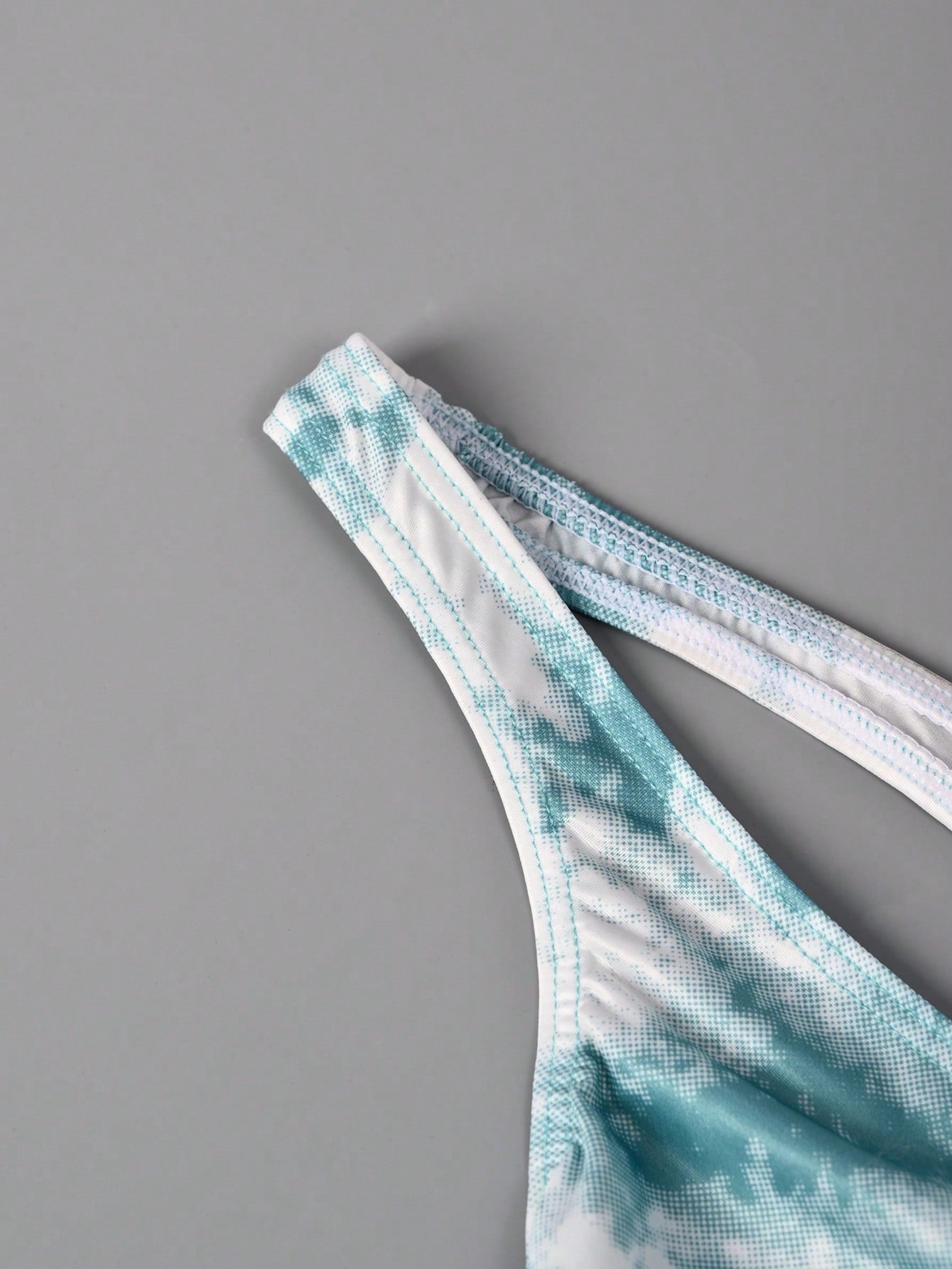 Men's tie dye thong underwear with a low rise fit and T-back design, made from polyester and elastane stretch fabric.