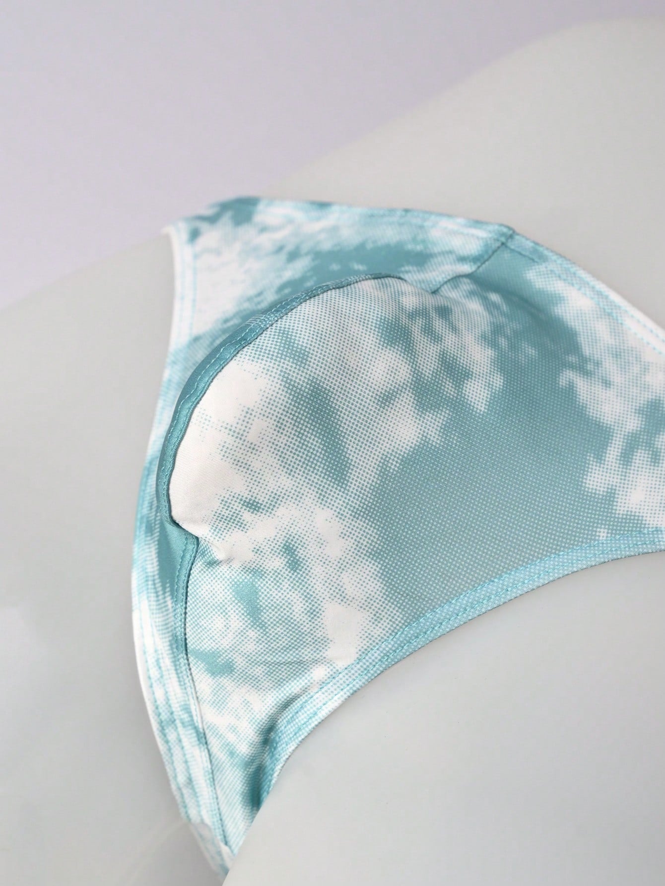 Men's tie dye thong underwear with a low rise fit and T-back design, made from polyester and elastane stretch fabric.