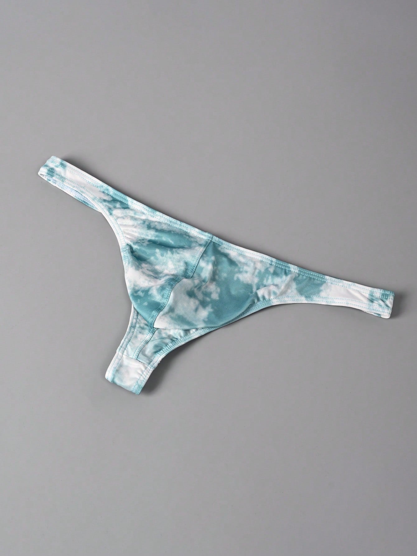 Men's tie dye thong underwear with a low rise fit and T-back design, made from polyester and elastane stretch fabric.