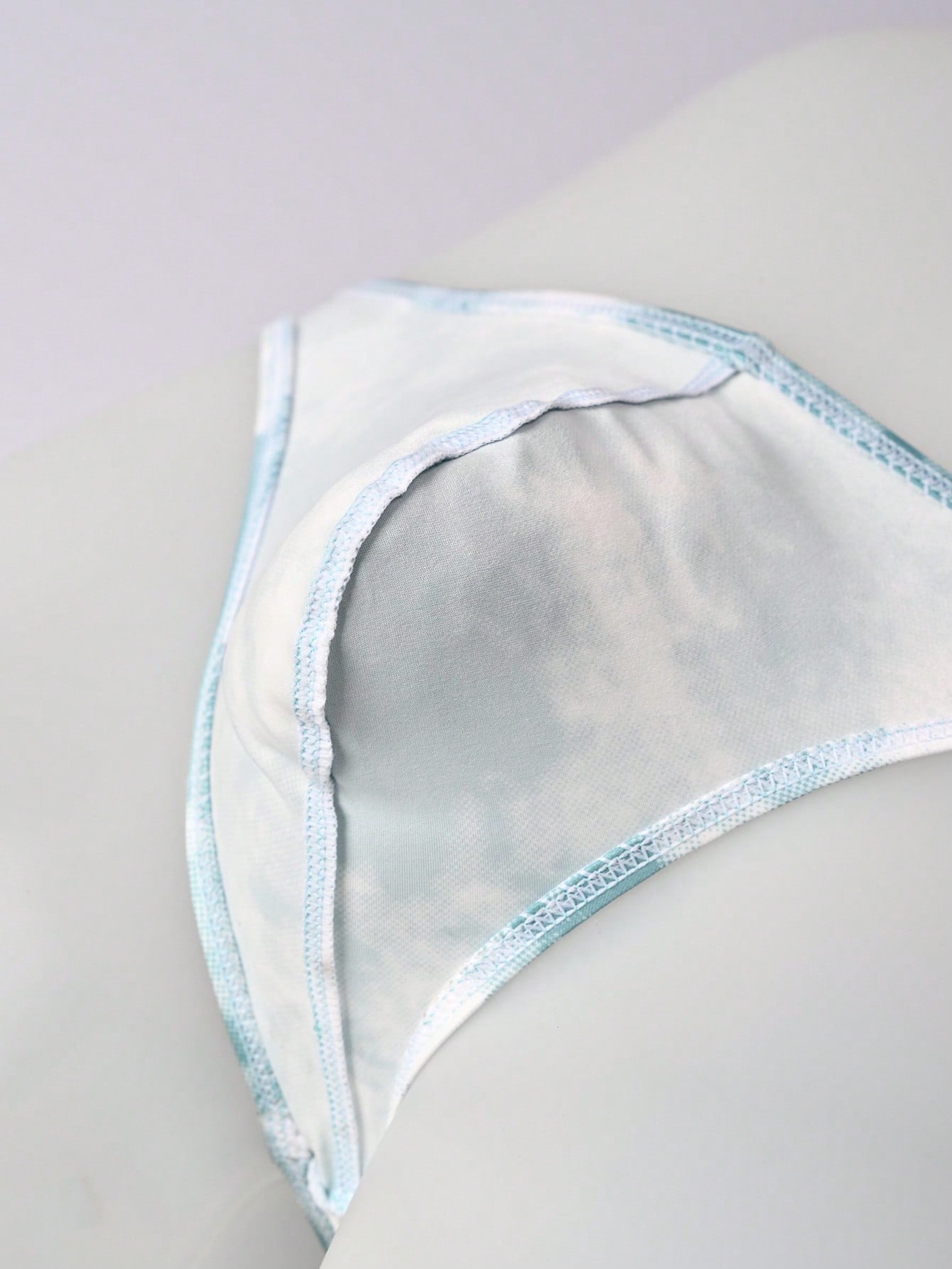 Men's tie dye thong underwear with a low rise fit and T-back design, made from polyester and elastane stretch fabric.