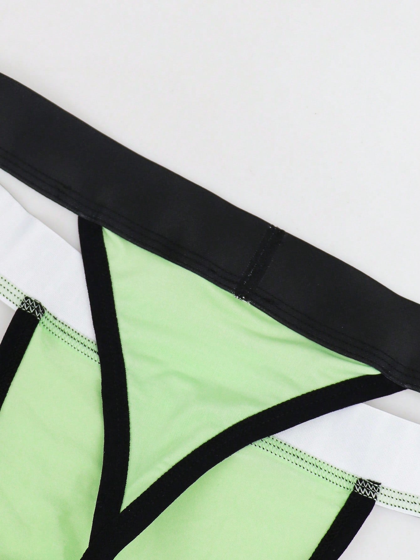 Men's low rise thong underwear in knitted fabric with striped colorblock pattern and letter waistband.
