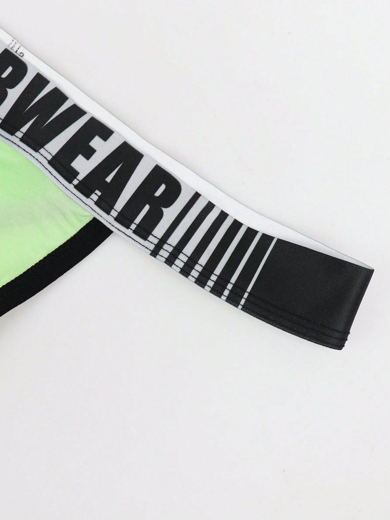 Men's low rise thong underwear in knitted fabric with striped colorblock pattern and letter waistband.