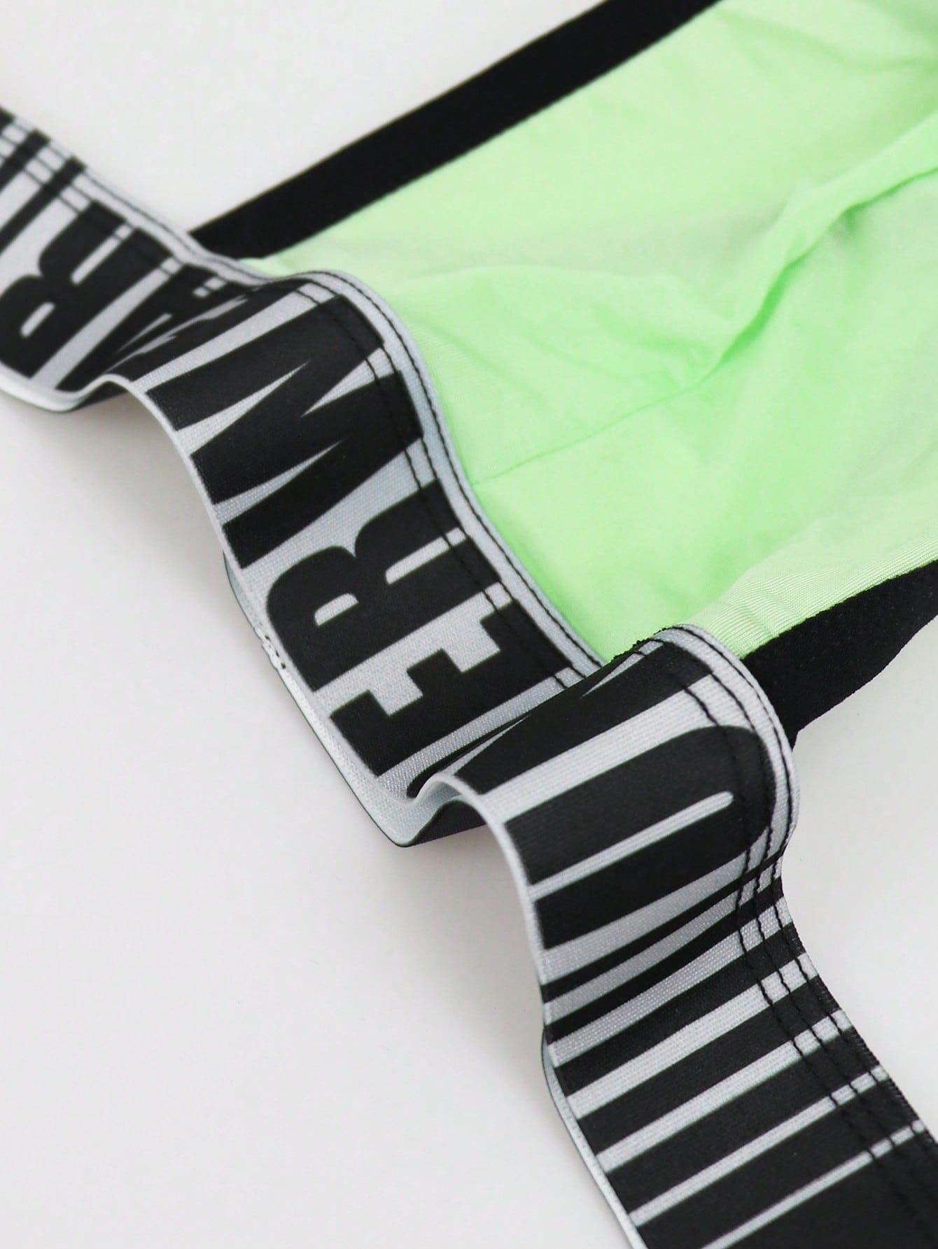 Men's low rise thong underwear in knitted fabric with striped colorblock pattern and letter waistband.
