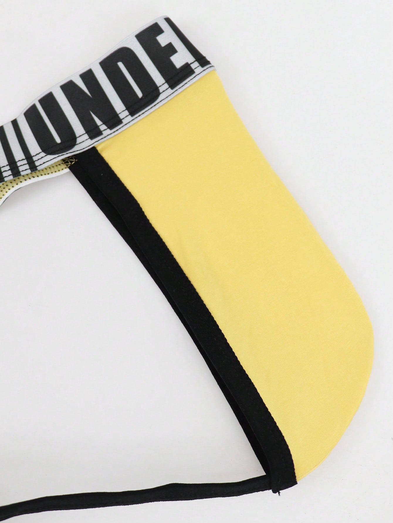 Men's low rise thong underwear in knitted fabric with striped colorblock pattern and letter waistband.