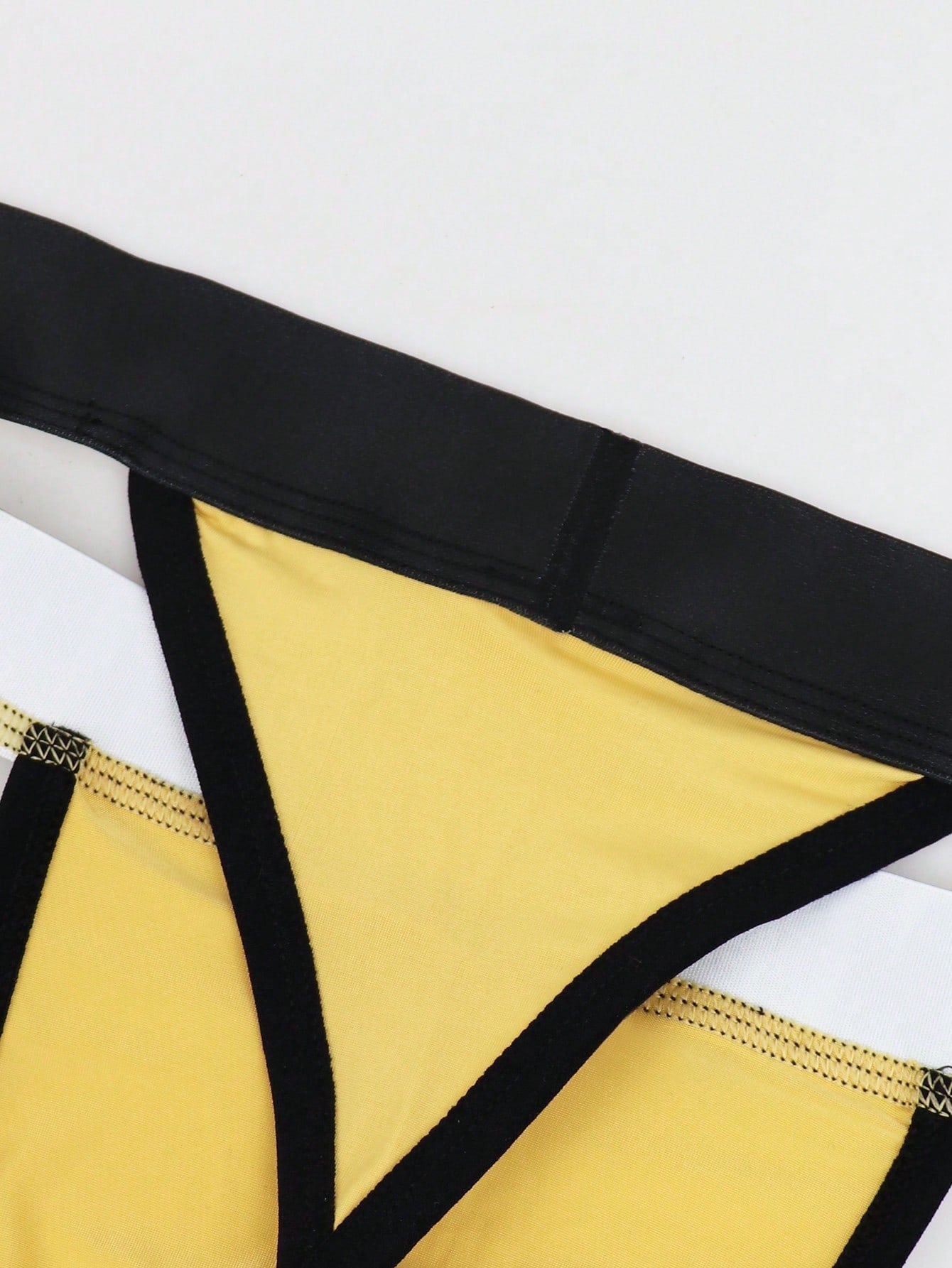 Men's low rise thong underwear in knitted fabric with striped colorblock pattern and letter waistband.