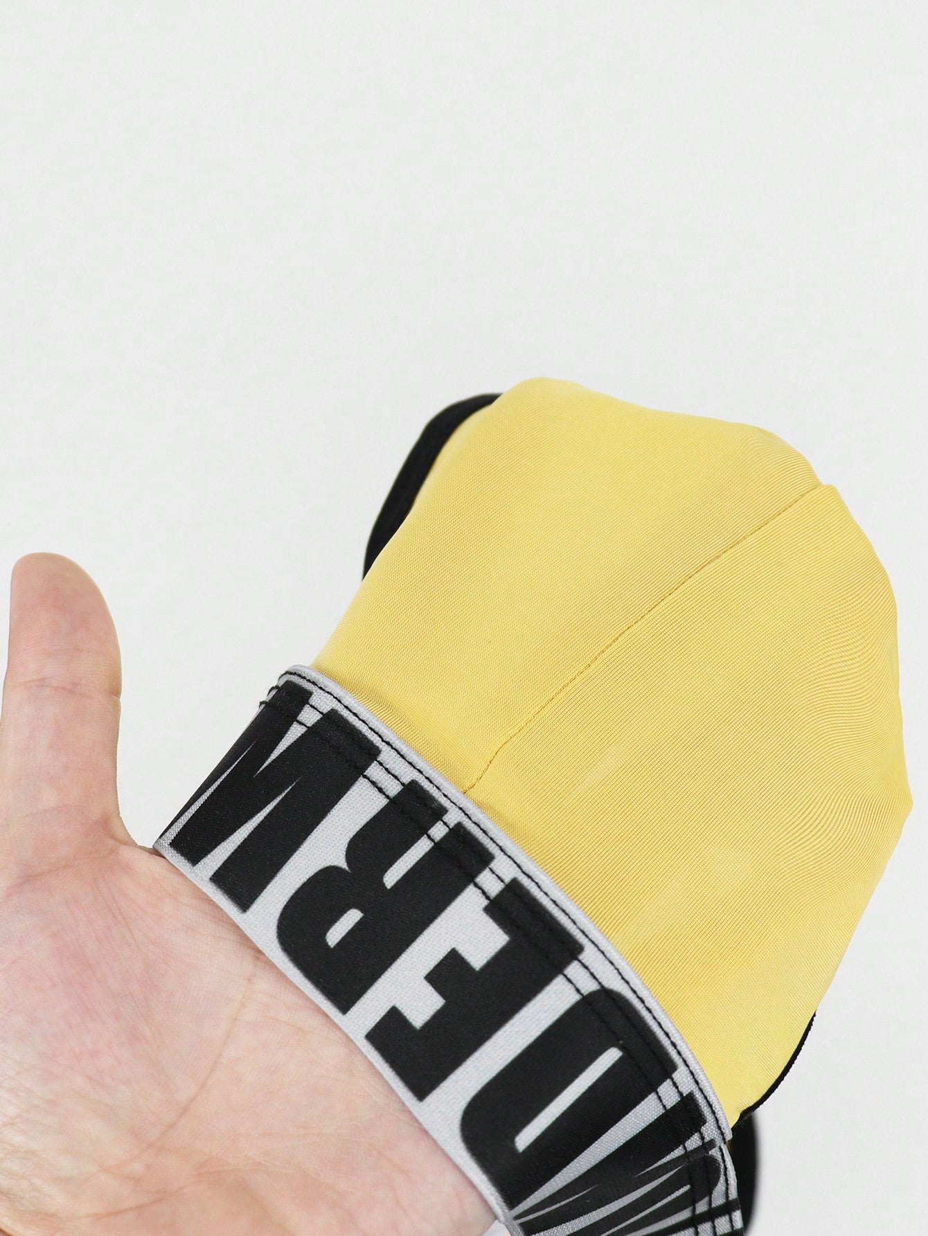 Men's low rise thong underwear in knitted fabric with striped colorblock pattern and letter waistband.