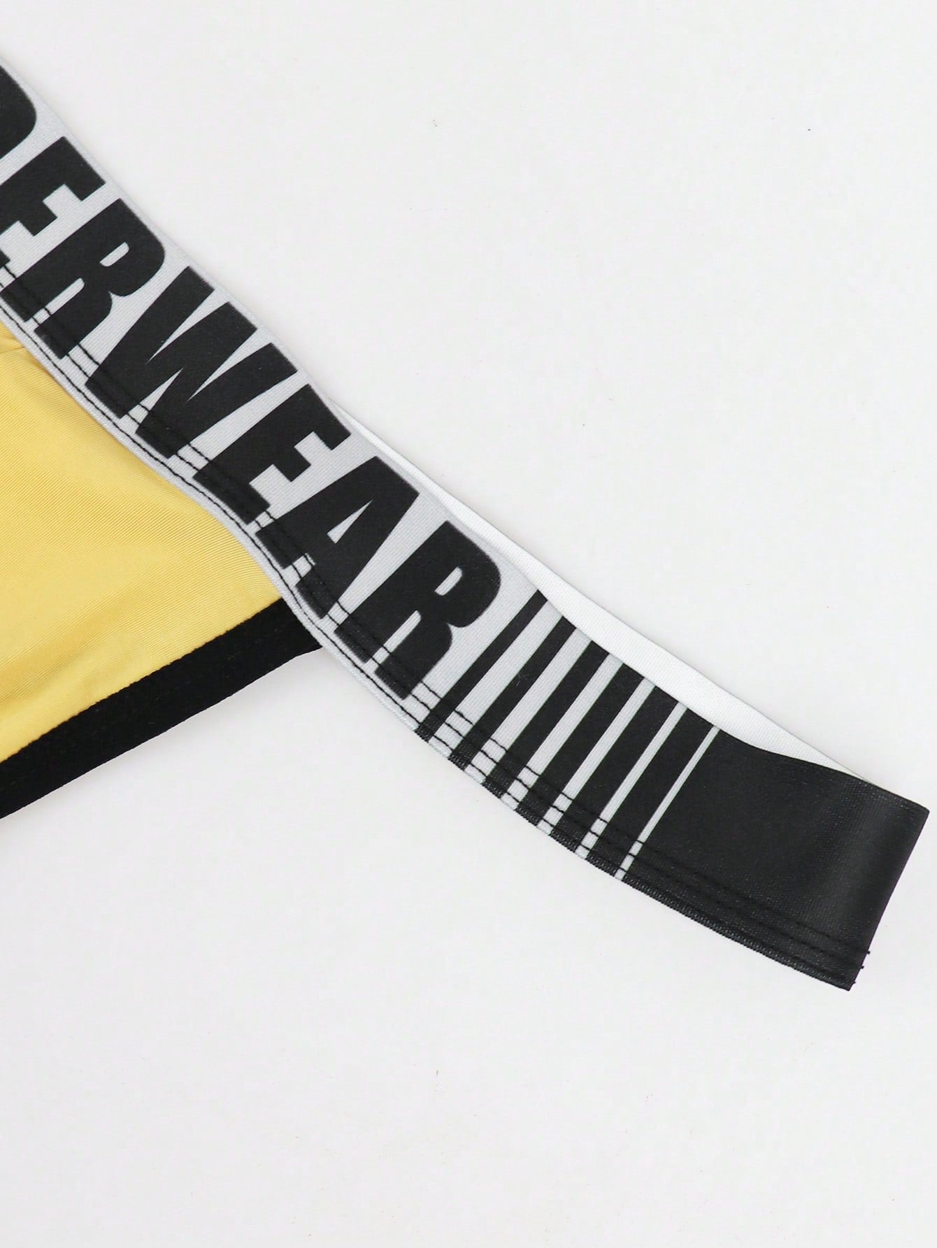 Men's low rise thong underwear in knitted fabric with striped colorblock pattern and letter waistband.