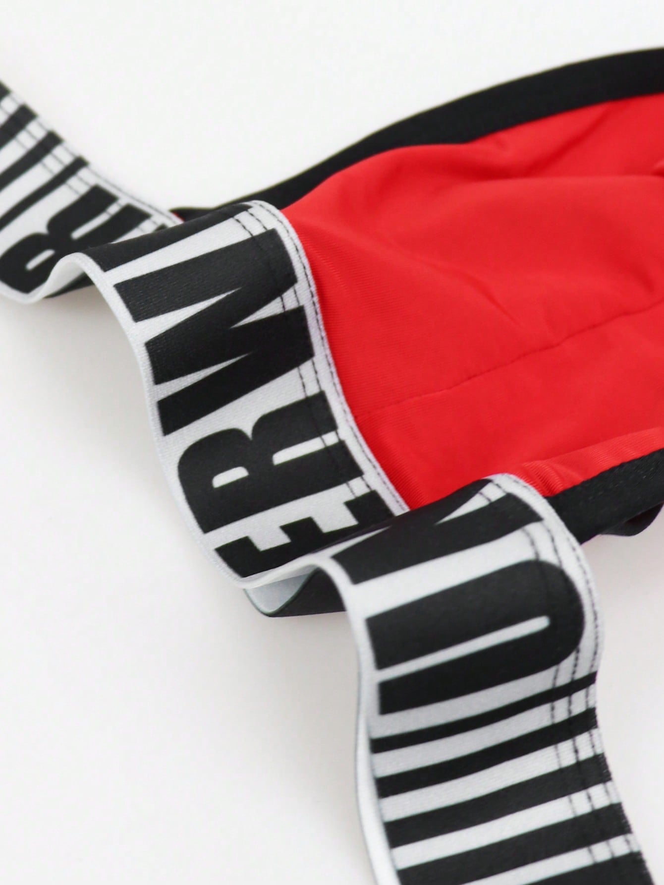 Men's low rise thong underwear in knitted fabric with striped colorblock pattern and letter waistband.