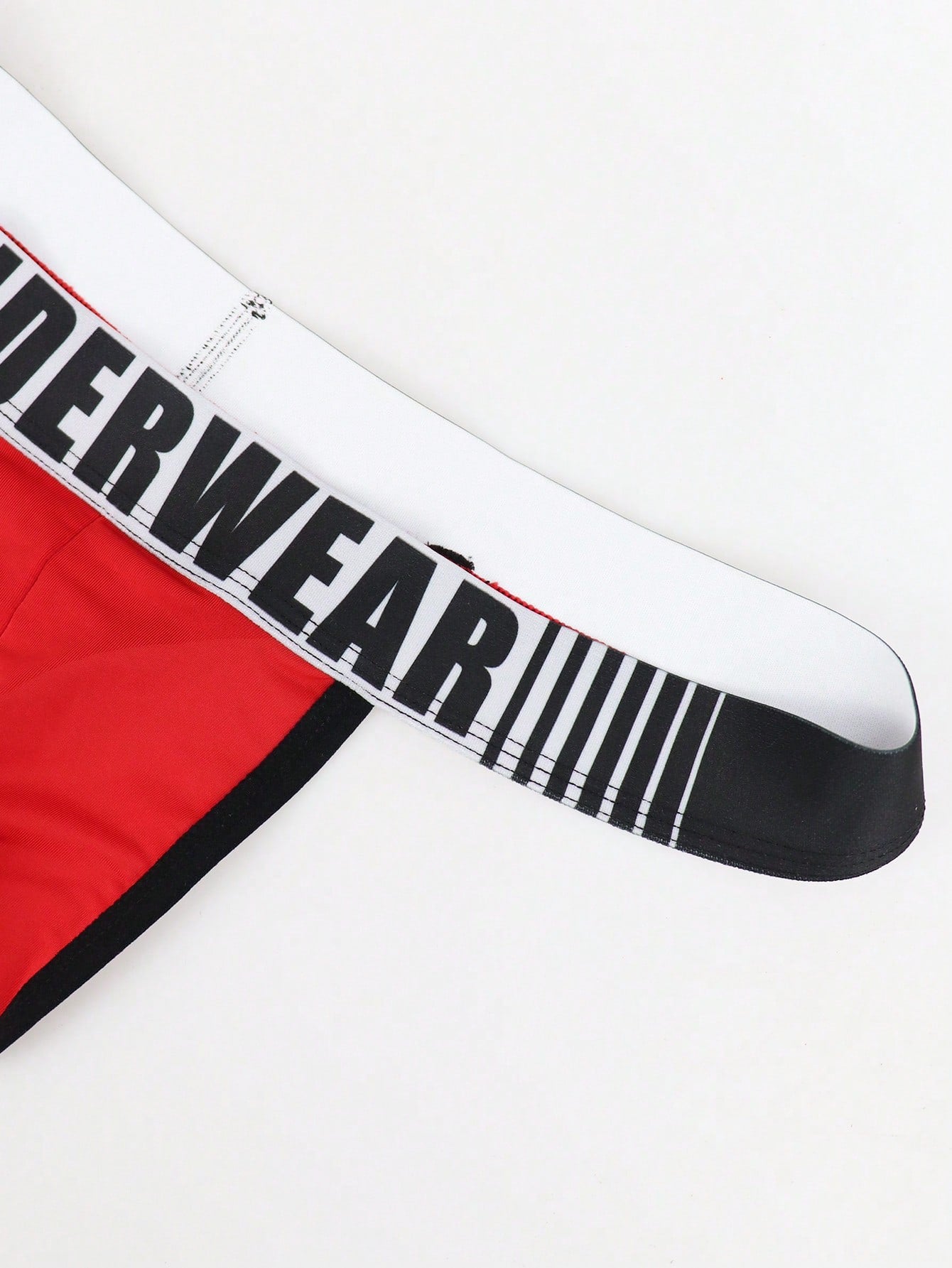 Men's low rise thong underwear in knitted fabric with striped colorblock pattern and letter waistband.