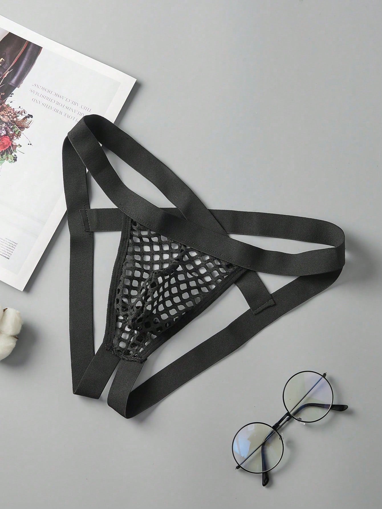 Black men's low rise thong underwear in semi-sheer mesh tulle with geometric pattern and criss cross cut-out detail.