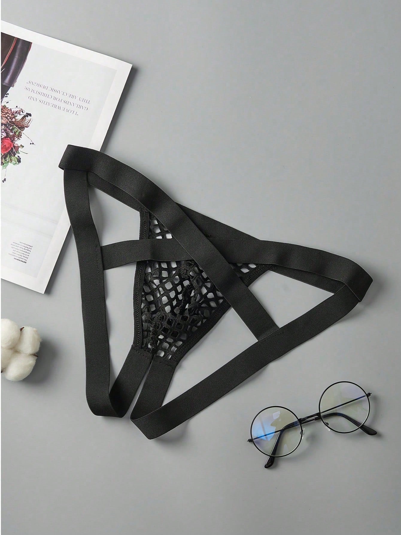 Black men's low rise thong underwear in semi-sheer mesh tulle with geometric pattern and criss cross cut-out detail.