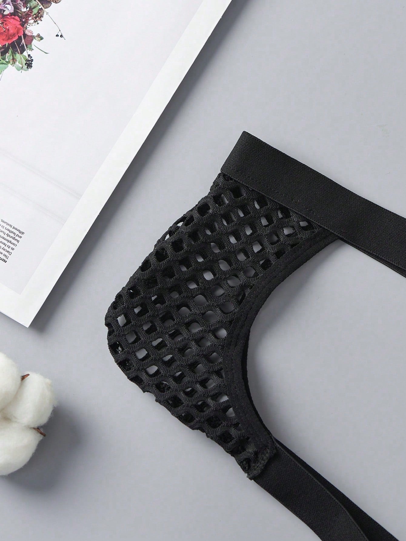 Black men's low rise thong underwear in semi-sheer mesh tulle with geometric pattern and criss cross cut-out detail.