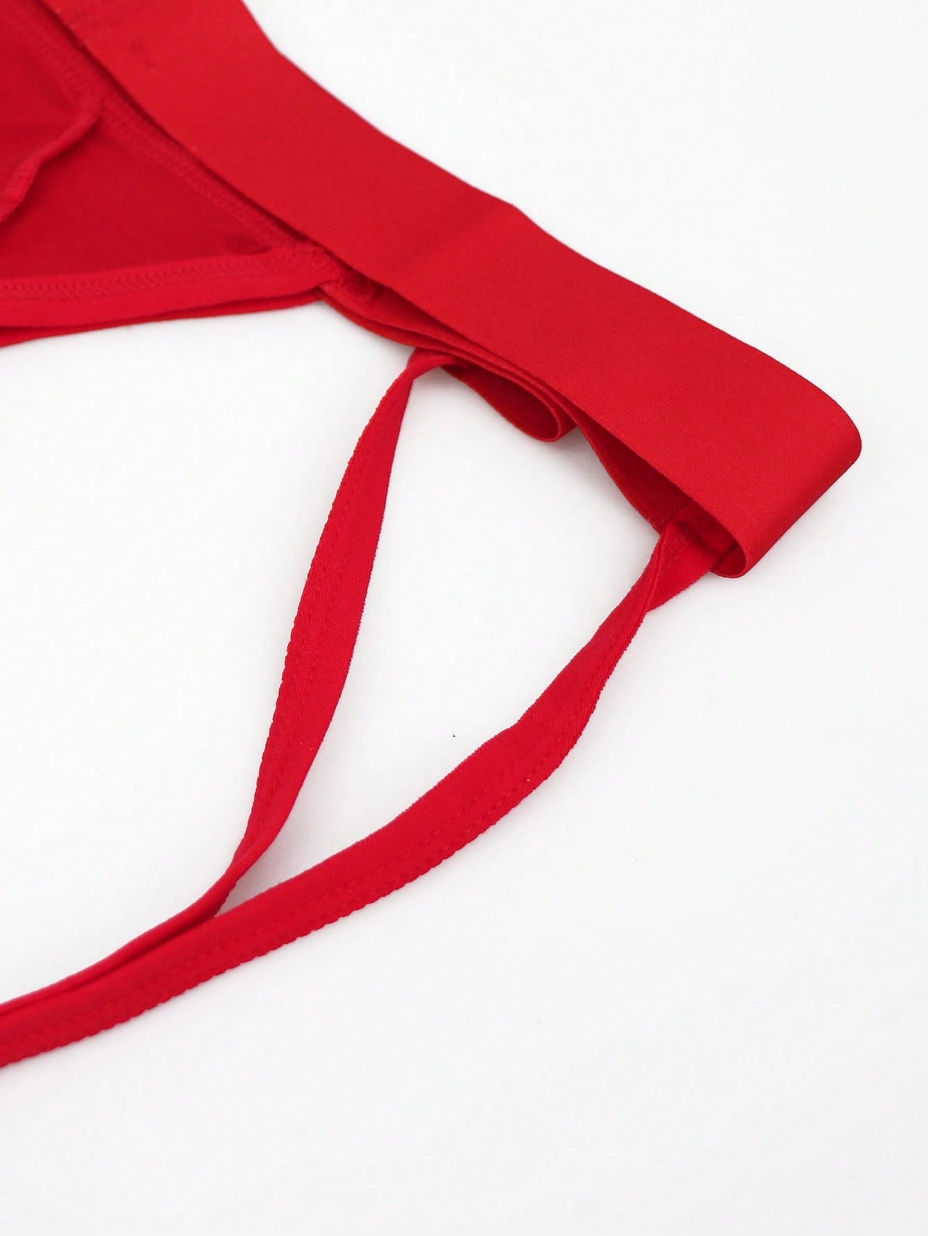 Men's red low-rise jockstrap underwear in knitted fabric with cut out detail, contrast binding, colorblock letter pattern, and medium stretch.