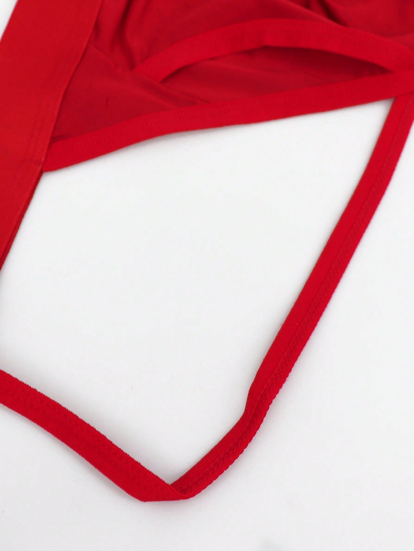 Men's red low-rise jockstrap underwear in knitted fabric with cut out detail, contrast binding, colorblock letter pattern, and medium stretch.