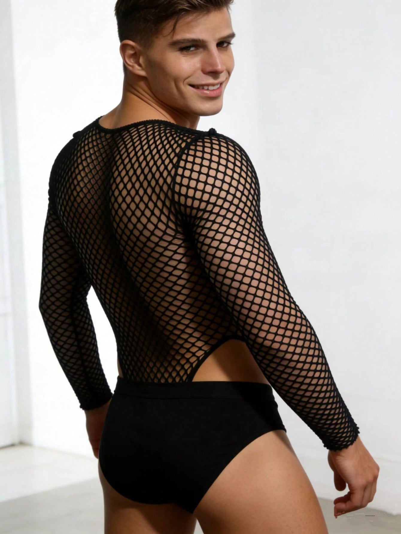Black men's fishnet bodysuit with lace detailing, round neck, mid-rise fit, and suspender-style design in high-stretch knitted polyamide fabric.