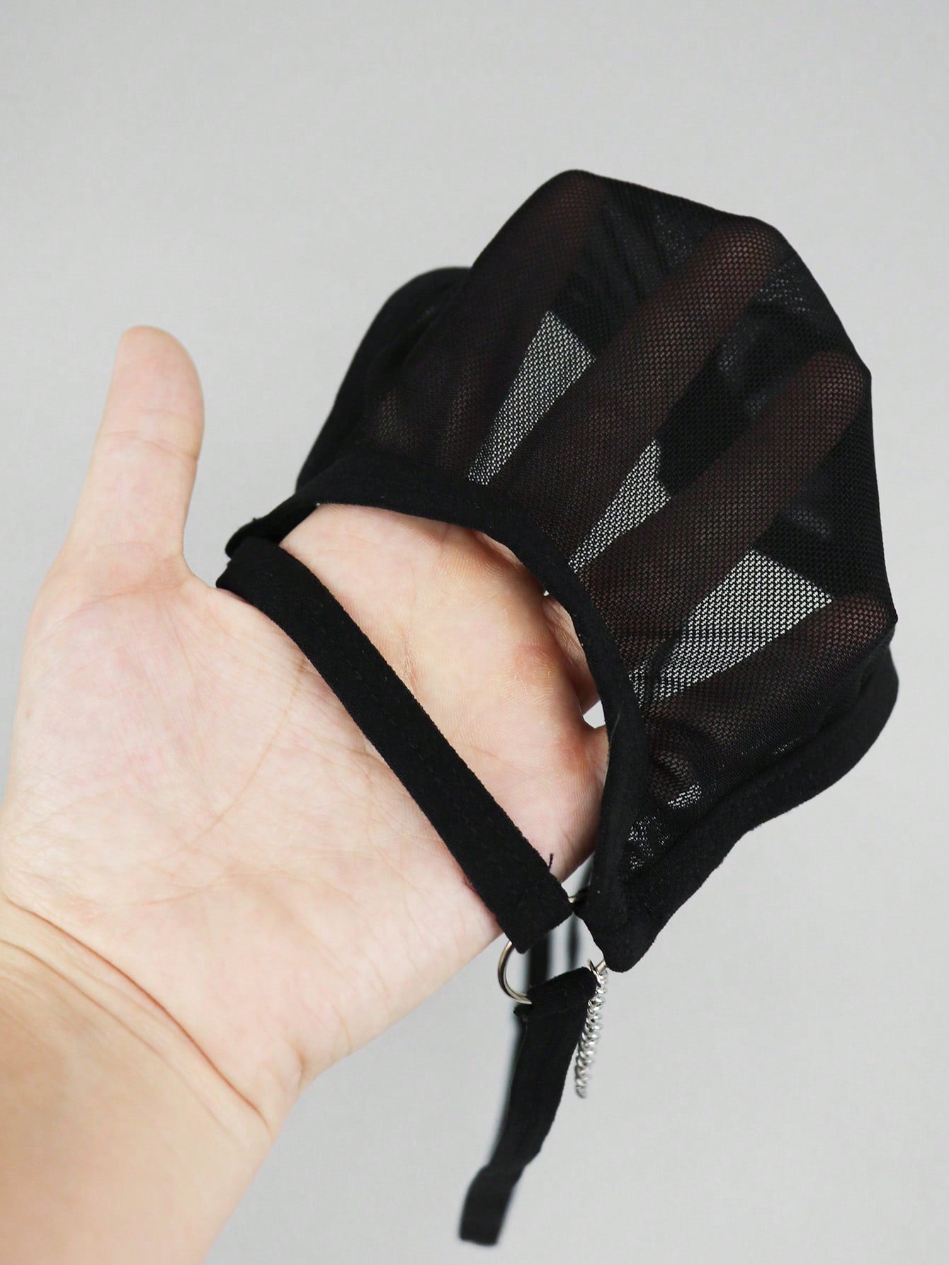 Men's black low rise mesh thong underwear with chain detail and colorblock design.