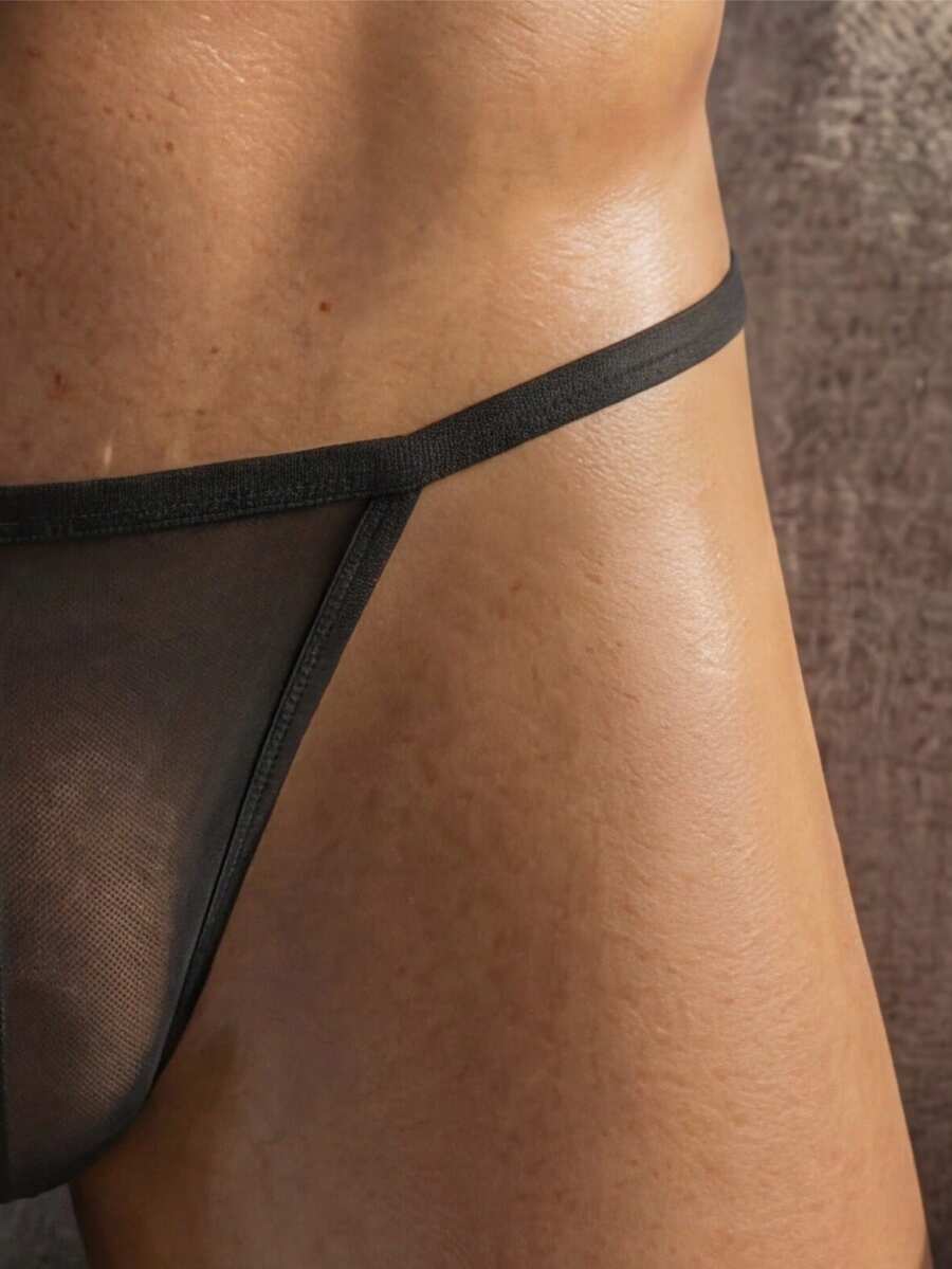 Plus size men's black semi-sheer low rise G-string thong underwear made of medium stretch knitted fabric.
