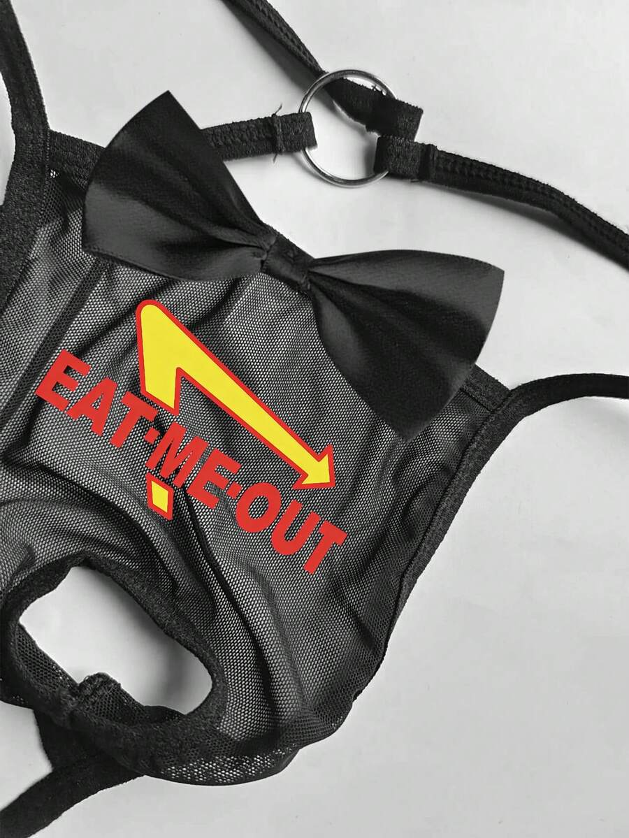 Black men's low rise open crotch G-string thong featuring letter print, bow decor, ring accent, and high stretch semi-sheer fabric.