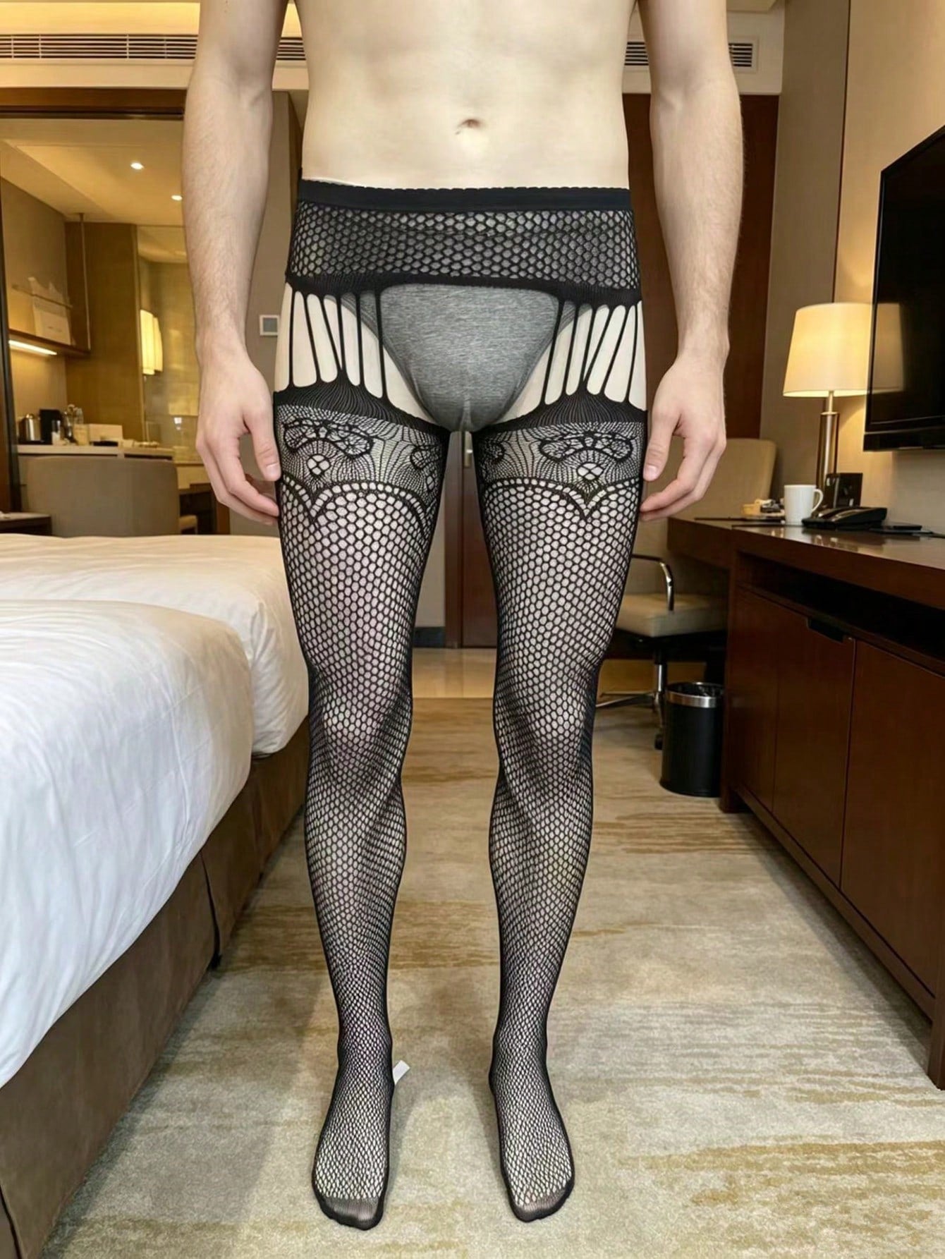 Men's fishnet bodystocking in black sheer knitted polyamide with hollow out detail, high stretch fabric, low rise design, and crotchless styling for party wear.