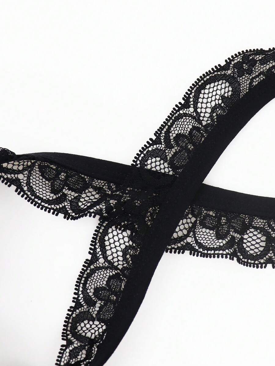 Black men's thong underwear featuring a low rise waist and letter pattern crafted from knitted stretch fabric.