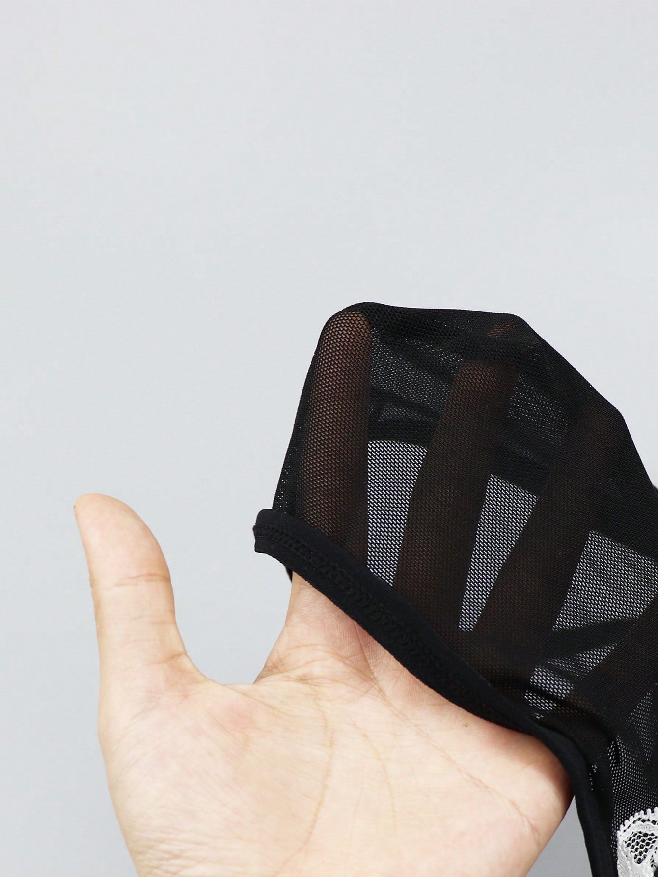 Men's mesh thong underwear with a mid-waist fit and black and white colorblock design.