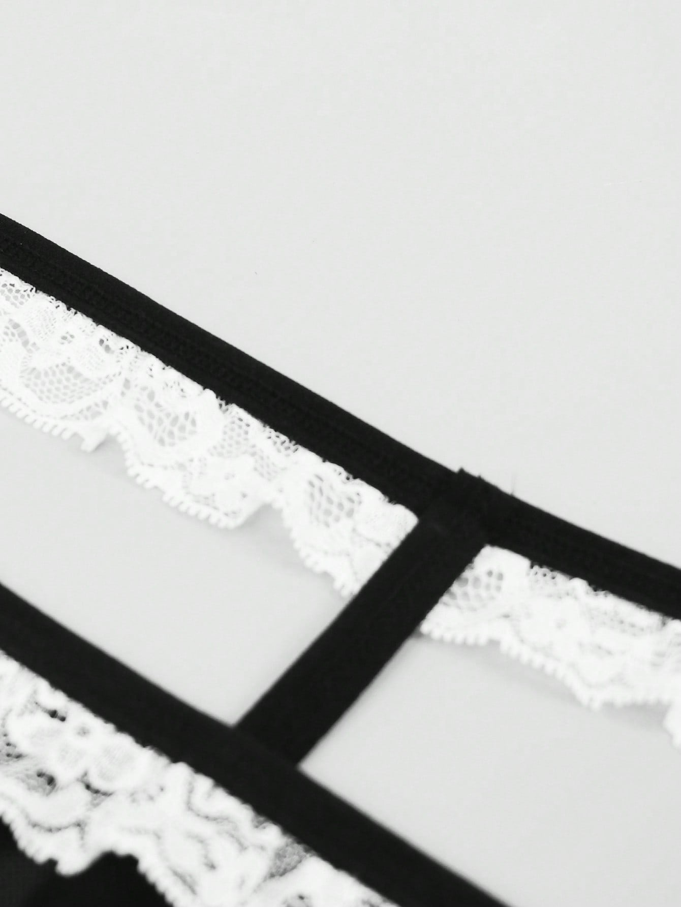 Men's mesh thong underwear with a mid-waist fit and black and white colorblock design.