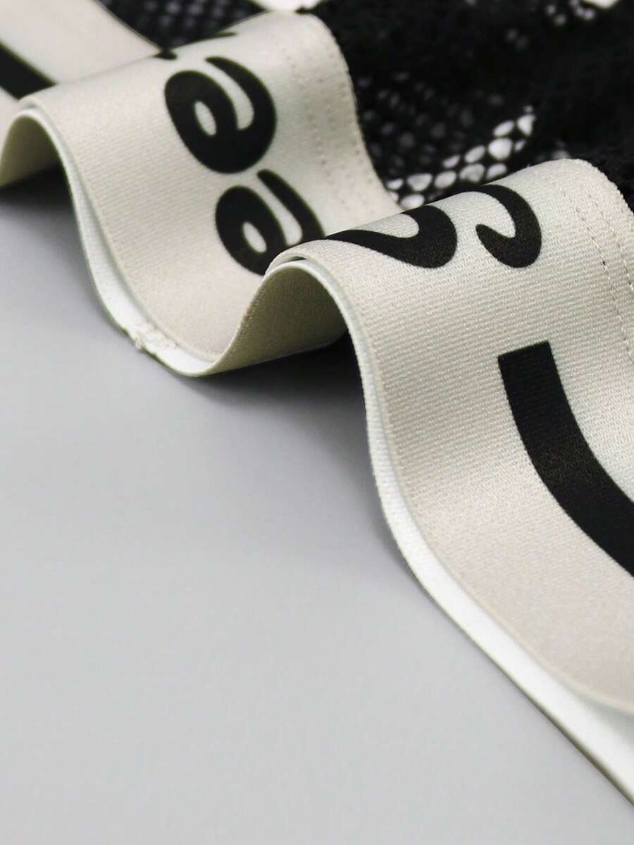 Black low-rise men's mesh briefs featuring contrast binding and tape details