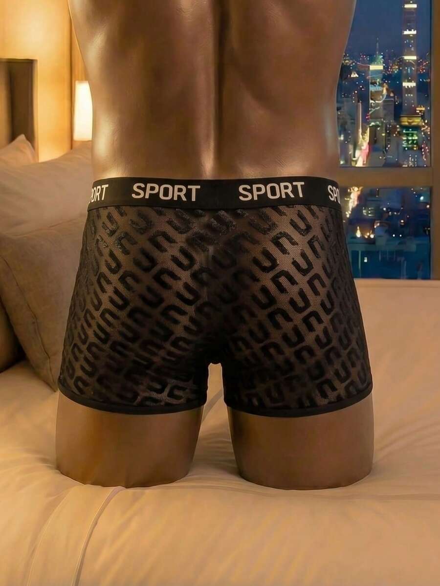 Men's black low rise boxer shorts featuring tape detail and letter pattern.