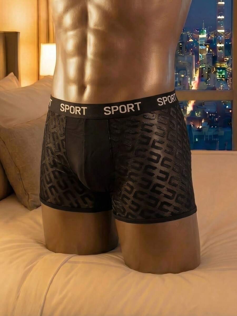 Men's black low rise boxer shorts featuring tape detail and letter pattern.