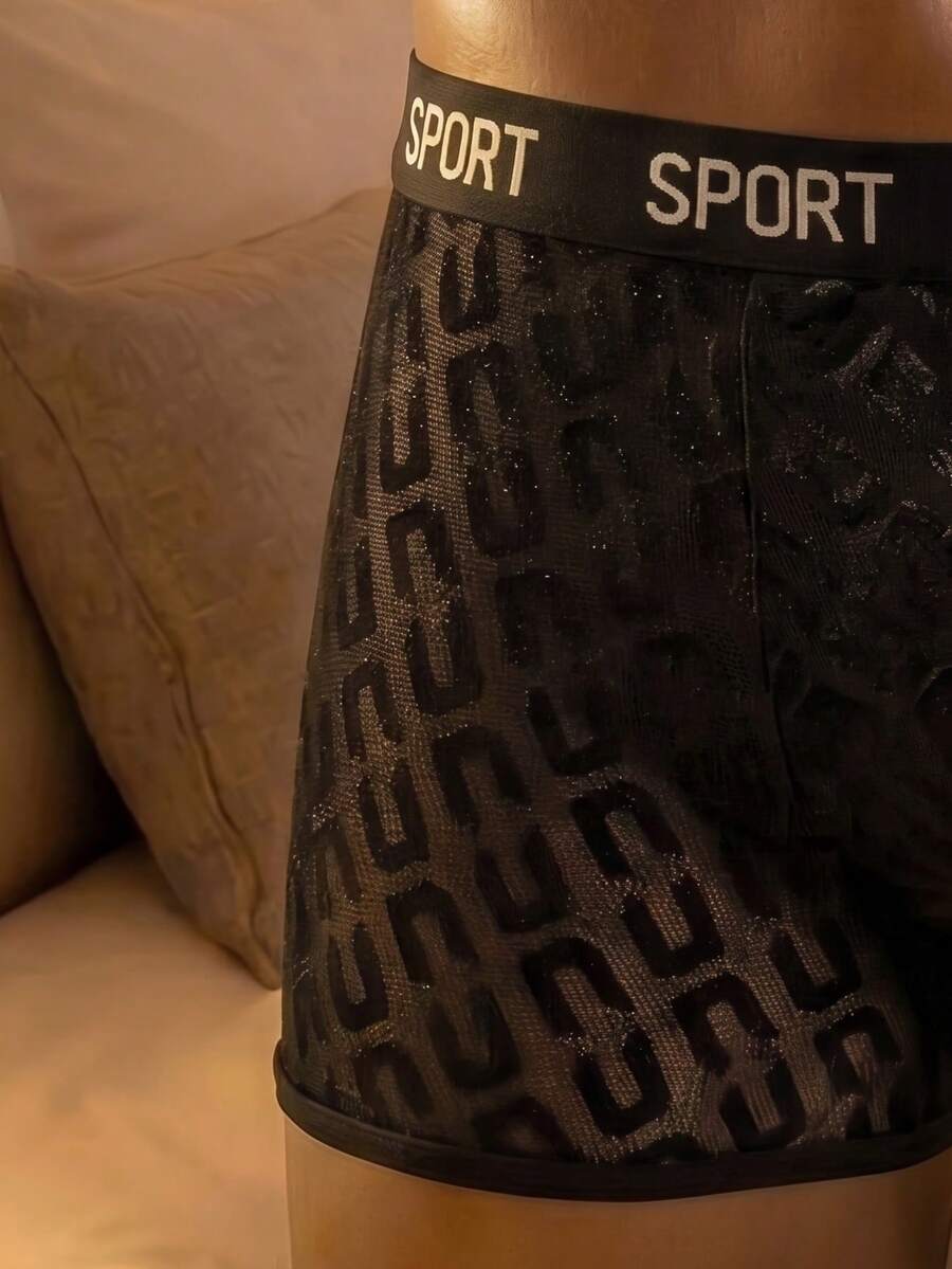 Men's black low rise boxer shorts featuring tape detail and letter pattern.