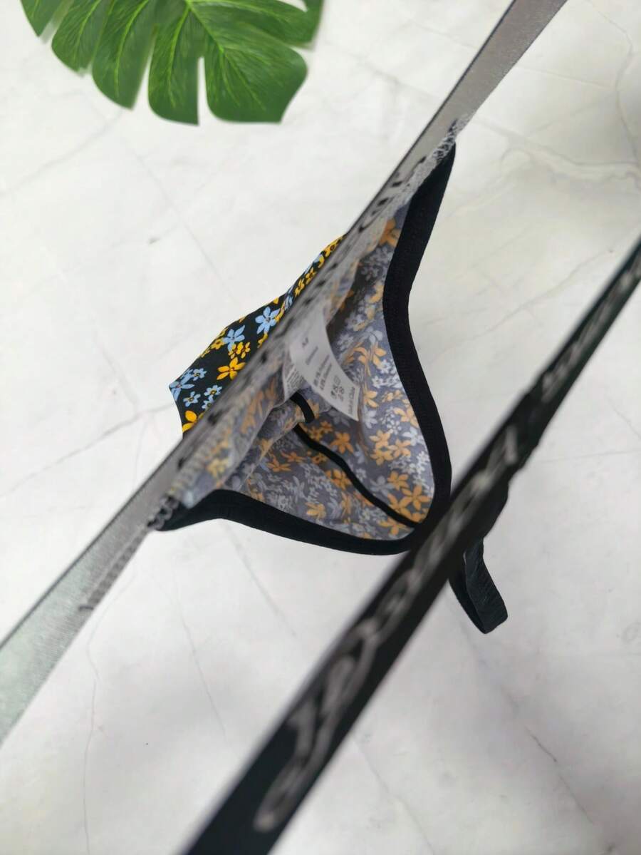 Black and white colorblock low-rise thong underwear for men featuring tape detail and knitted stretch fabric.