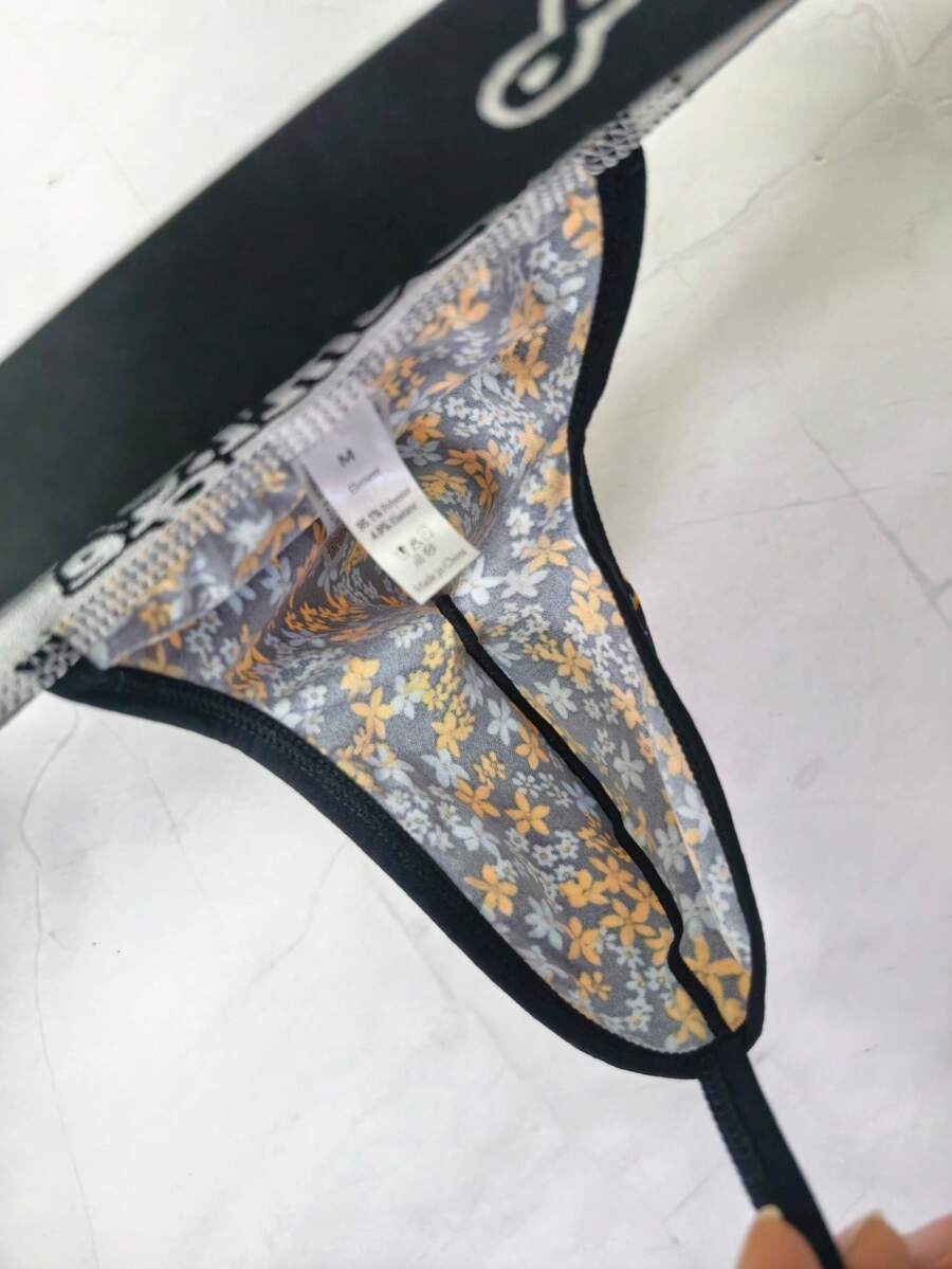 Black and white colorblock low-rise thong underwear for men featuring tape detail and knitted stretch fabric.