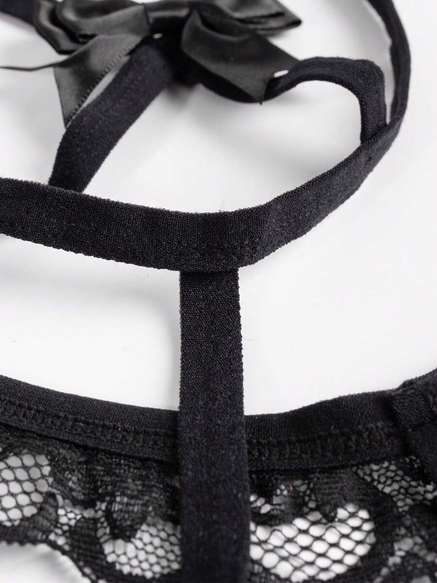 Black low-rise men's thong underwear with bow waist accent made of knitted fabric