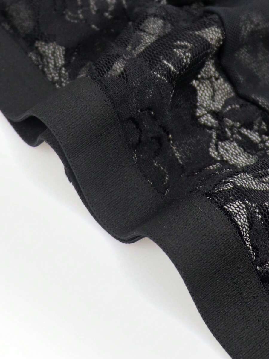 Men's black low rise sheer mesh thong with plant pattern detail.