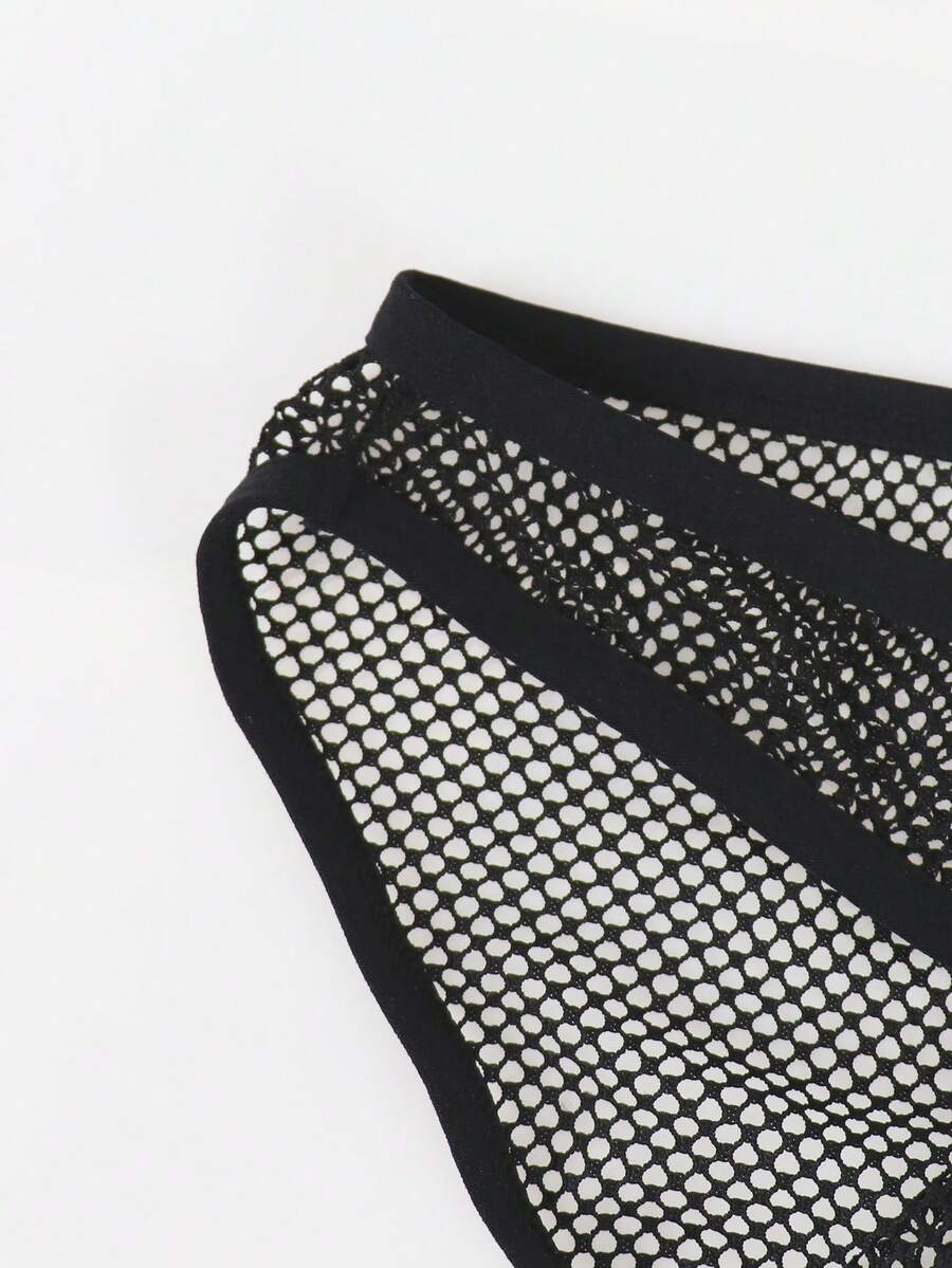 Black men's thong underwear featuring mesh fabric, cut out details, letter pattern, and a low rise fit.