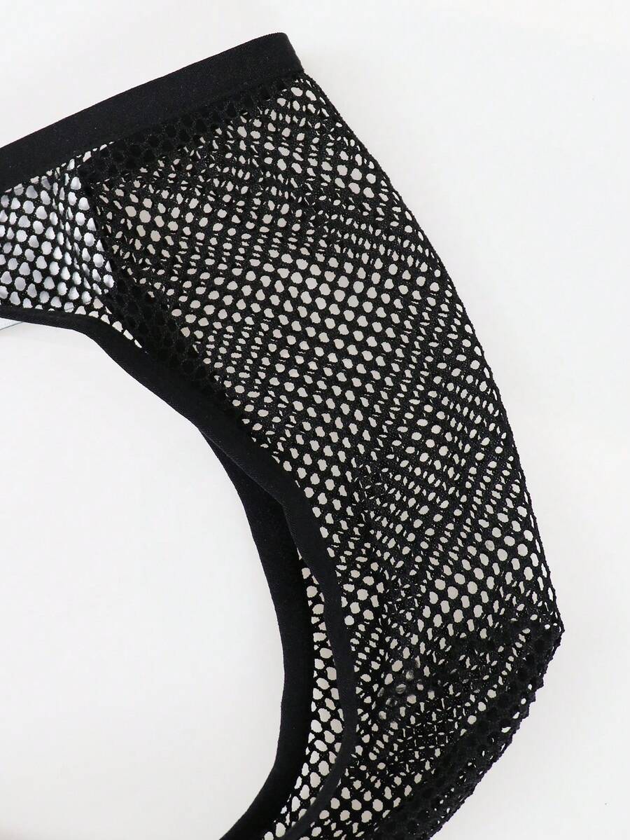 Black men's thong underwear featuring mesh fabric, cut out details, letter pattern, and a low rise fit.