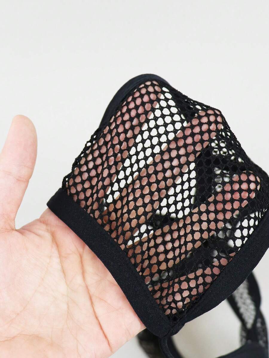Black men's thong underwear featuring mesh fabric, cut out details, letter pattern, and a low rise fit.