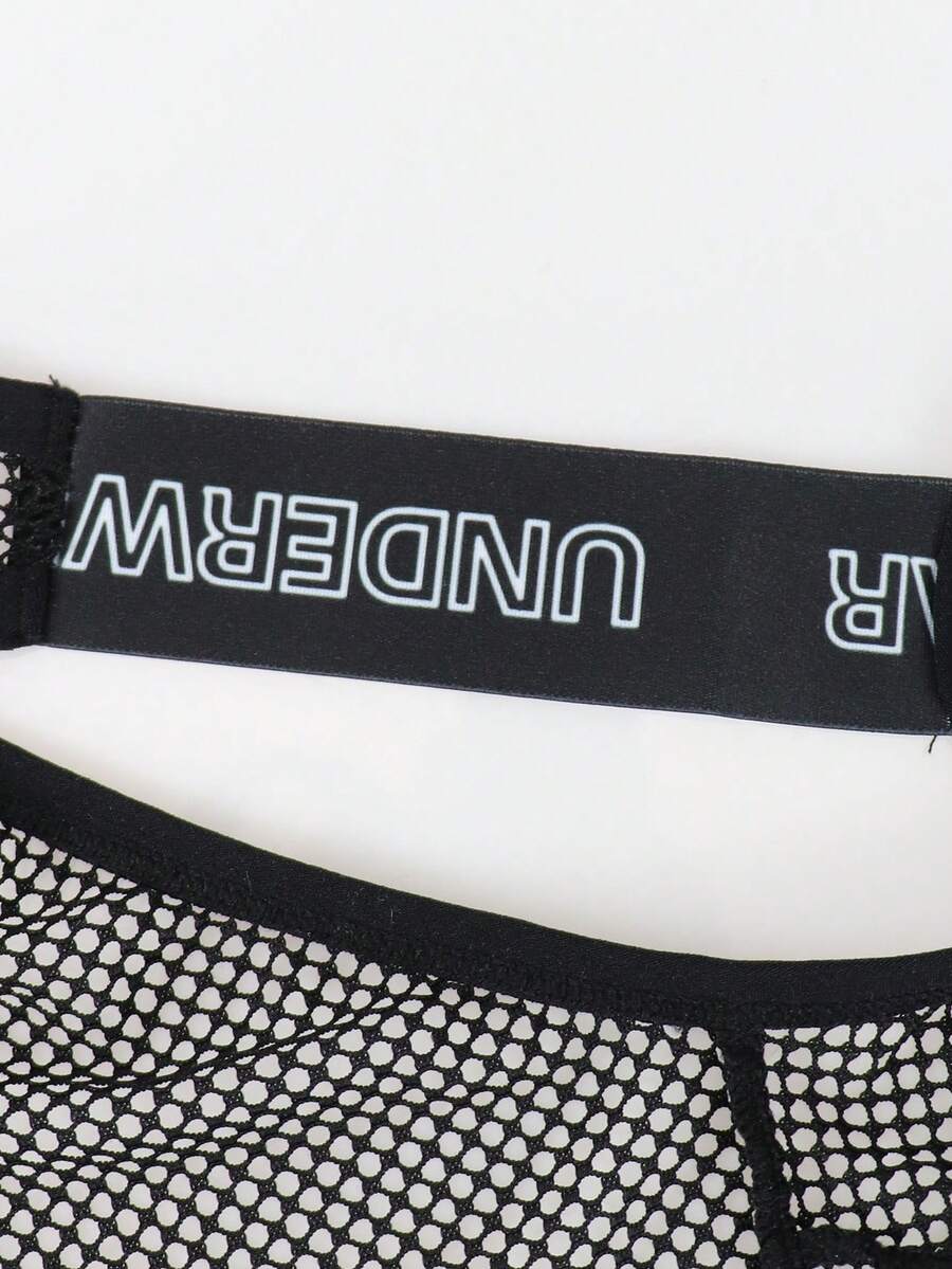 Black men's thong underwear featuring mesh fabric, cut out details, letter pattern, and a low rise fit.