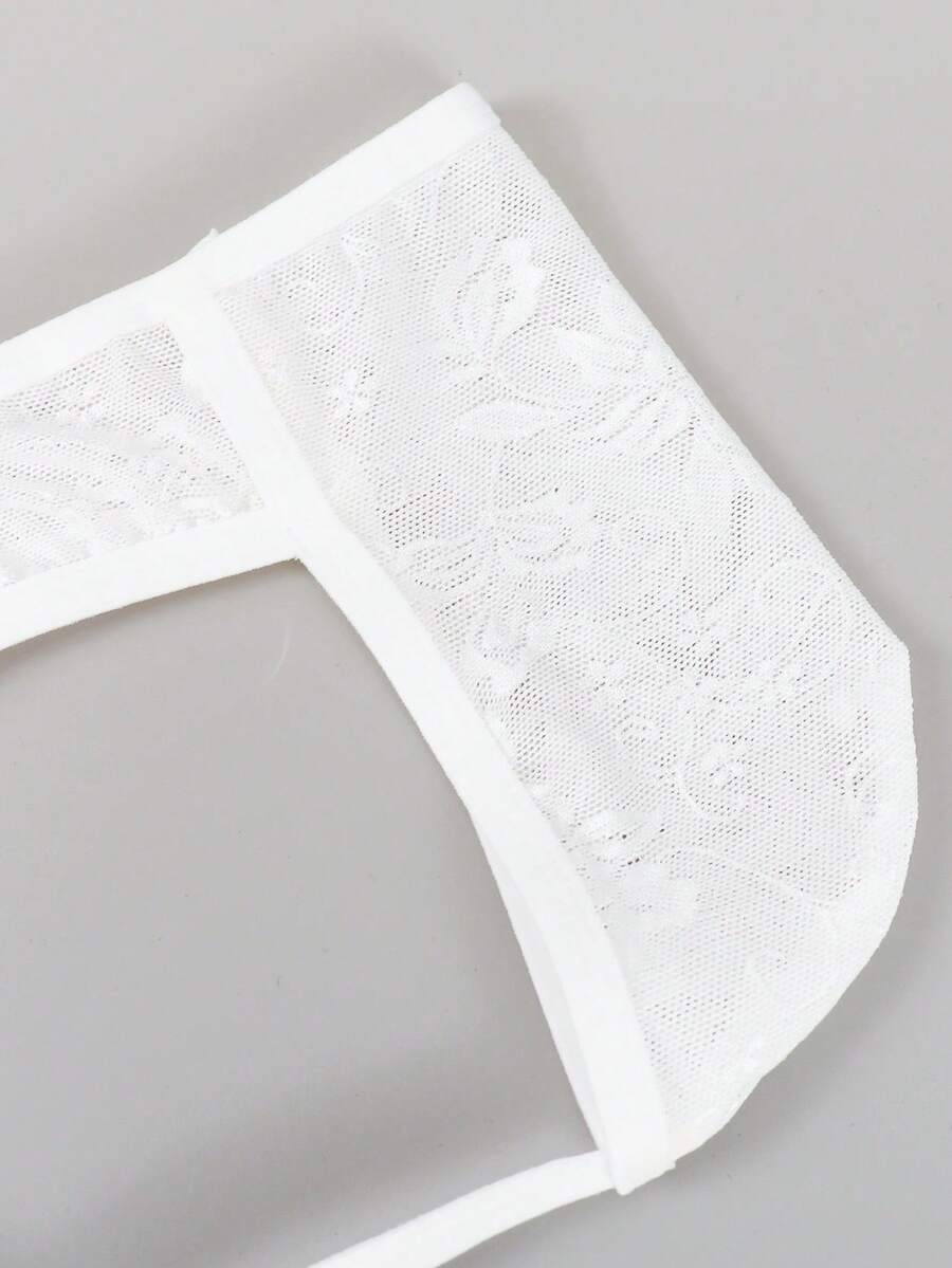 White lace thong underwear for men featuring a low rise waist and plant pattern knitted fabric.