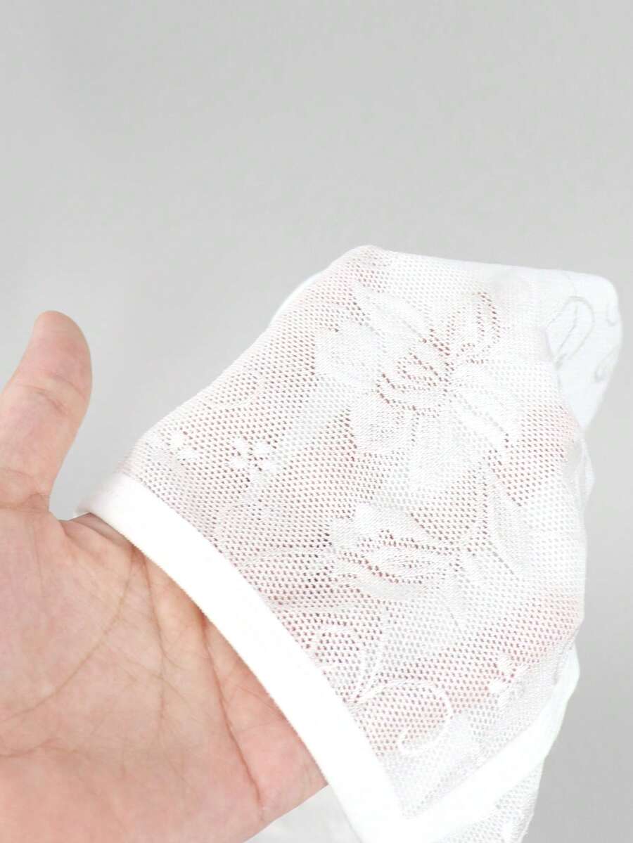 White lace thong underwear for men featuring a low rise waist and plant pattern knitted fabric.